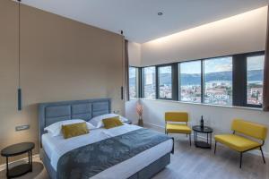 um quarto com uma cama, 2 cadeiras e janelas em Seascape Luxury Rooms em Split