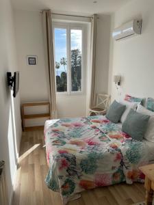 Un dormitorio con una cama con una manta de flores y una ventana en Hôtel La Villa Patricia - Charme et Tradition, en Villefranche-sur-Mer