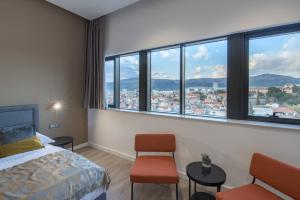 um quarto de hotel com uma cama, cadeiras e janelas em Seascape Luxury Rooms em Split