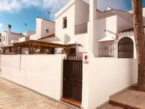 ein weißes Haus mit einem Tor und einem Zaun in der Unterkunft Duplex Las Torres La Barrosa 4 Bedrooms By Chiclana Dreams - A 750 m de la playa in Chiclana de la Frontera