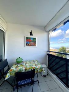 a room with a table and chairs and a balcony at Appartement vue mer in Le Moule