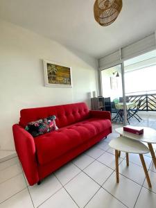 a red couch in a living room with a table at Appartement vue mer in Le Moule