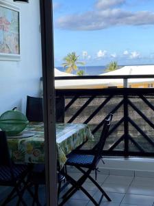 un tavolo e sedie su un balcone con vista sulla spiaggia di Appartement vue mer a Le Moule