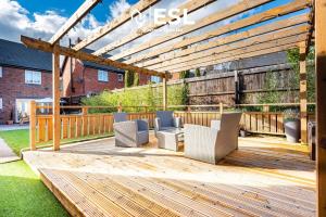 a wooden deck with chairs and a pergola at Large Modern 4 Bedroom House in Uttoxeter, Near Alton Towers, Great for Families in Uttoxeter