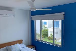 ein blaues Schlafzimmer mit einem Fenster und einem Deckenventilator in der Unterkunft Condo Apulo - Hermosa casa - Jacuzzi y Piscina privados - WiFi in Apulo