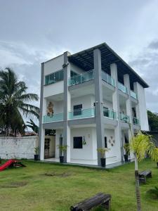 圣阿马鲁Eco House Gaivota - Cond Ville Portal das Dunas的一栋白色建筑，前面有一棵棕榈树