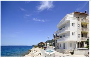 a white building with a boat in front of the water at Apartmani Mira in Drasnice