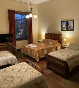 a hotel room with two beds and a television at Hostal Residencia en el Cerro in Valparaíso