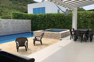 eine Terrasse mit Stühlen, einem Tisch und einem Pool in der Unterkunft Condo Apulo - Hermosa casa - Jacuzzi y Piscina privados - WiFi in Apulo