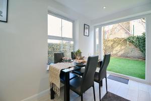 comedor con mesa, sillas y ventana en Fabulous 3 bed NW London apartment with private garden, en Londres