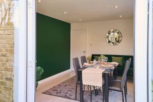 ロンドンにあるFabulous 3 bed NW London apartment with private gardenの緑の壁のダイニングルーム(椅子とテーブル付)