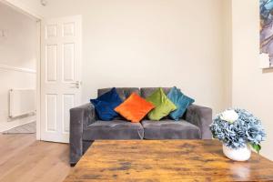 a living room with a couch with colorful pillows on it at 3-bedroom Home in Liverpool L15 with FREE Parking in Liverpool