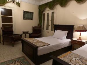 a bedroom with a bed and two chairs and a lamp at Grand Museum Guest House in Kafr Abū ʼumaydah