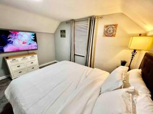 1 dormitorio con 1 cama blanca y TV de pantalla plana en Stylish Cape Cod Cutie All Queen Beds 13 Min to downtown, en Cincinnati
