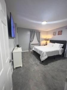 1 dormitorio con 1 cama blanca y TV en Stylish Cape Cod Cutie All Queen Beds 13 Min to downtown, en Cincinnati