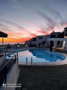 a large swimming pool with a sunset in the background at Great Ocean View and Lobos & Fuerteventura Islands in Tías