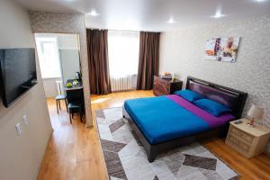 a bedroom with a blue bed and a television at 1 комнатная квартира в центре на Пушкина 92 in Kostanay