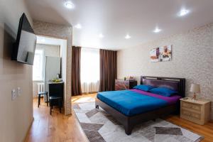 1 dormitorio con 1 cama azul y TV en 1 комнатная квартира в центре на Пушкина 92 en Kostanái