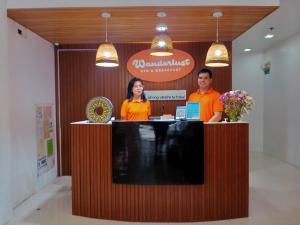 a man and a woman standing behind a counter at Wanderlust Bed & Breakfast in Puerto Princesa City