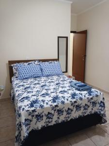 um quarto com uma cama com um cobertor azul e branco em Quarto Divas na Sakura House em Indaiatuba