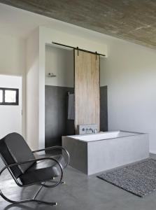 a bathroom with a chair and a bath tub at Le Moment Posada Boutique in Colonia del Sacramento