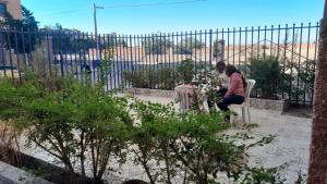 a woman sitting at a table in front of a fence at Hostel artistic airport in Marrakech