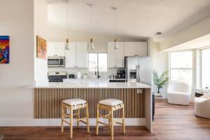 a kitchen with white cabinets and a counter with two stools at Heated Pool and Jacuzzi, Scenic Mountain View, Lux and Cozy, in Cottonwood