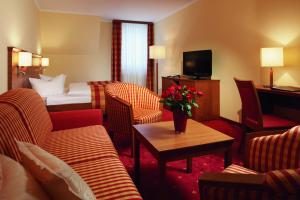 una camera d'albergo con divani, letto e tavolo di Parkhotel Neustadt a Neustadt in Sachsen