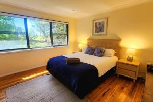卡頓巴的住宿－Narrow Neck Views - Peaceful 4 Bedroom Home with Stunning Views!，一间卧室设有一张大床和两个窗户。