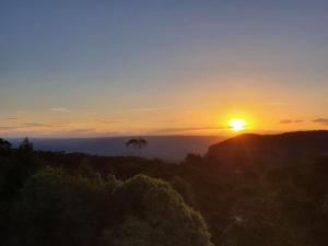 a sunset with the sun setting on a mountain at Narrow Neck Views - Peaceful 4 Bedroom Home with Stunning Views! in Katoomba