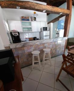 eine Küche mit einer Theke mit zwei Hockern in einem Zimmer in der Unterkunft Praia de Guaibim - Casa de praia 2Q - 2 suítes com ar - em condomínio a 300m da praia in Guaibim