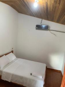 ein Schlafzimmer mit einem weißen Bett mit einem Licht an der Wand in der Unterkunft HOSTAL ESPERANZA in Palomino