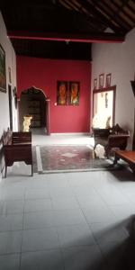 una stanza con due pianoforti e una parete rossa di Ibu Ana Homestay a Tabanan