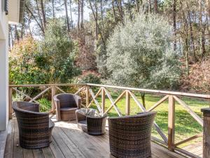 eine Veranda mit Korbstühlen und einem Tisch auf einer Terrasse in der Unterkunft Villa avec piscine privée, jardin clôturé et WIFI à Biscarrosse - Idéale pour 6 personnes - FR-1-521-192 in Biscarrosse