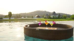 楠府的住宿－Pim Pool Villa Nan，水边柳条桌边的三杯鸡尾酒