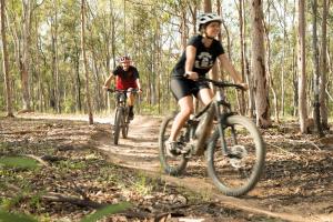 two people riding bikes on a trail in the woods at Spicers Hidden Vale in Grandchester