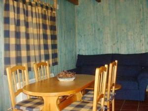 a dining room table and chairs with a blue couch at El Muerdago de Cañada in Cañada del Hoyo