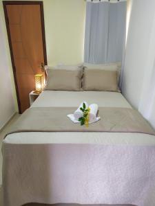a bed with two white flowers on top of it at Pousada Barreirinhas House in Barreirinhas