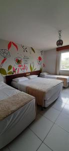 a bedroom with two beds and a wall with flowers at Porto Carleto Temporadas - Quarto no Portobello Park Hotel in Porto Seguro