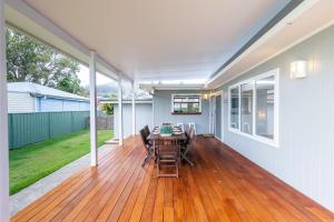 un patio con mesa y sillas en un suelo de madera en Shoalz Renovated Cottage and Boat Parking, en Shoal Bay