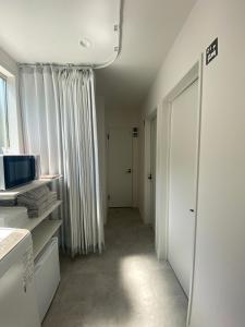 um quarto com um corredor com paredes brancas e uma janela em Guest House DARUMA em Anan
