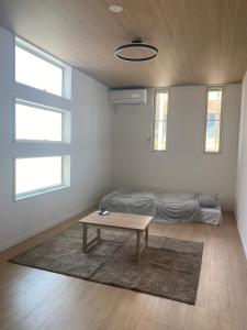 a living room with a table and a bed at Guest House DARUMA in Anan