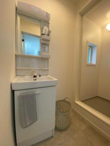 a white bathroom with a sink and a mirror at Guest House DARUMA in Anan