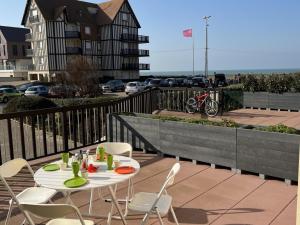 stół i krzesła na patio z budynkiem w obiekcie Appartement 3 pièces avec terrasses et vue mer - Parking inclus - FR-1-487-349 w mieście Cabourg