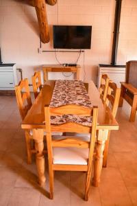 a wooden table with chairs and a television in a room at Cabañas Las Nubes in Puerto Deseado