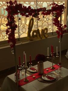 uma mesa com uma toalha de mesa branca e flores vermelhas em Marina em Sohar