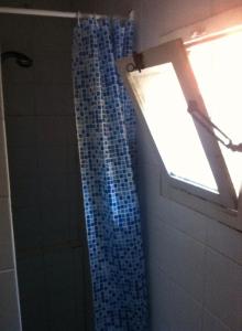 a bathroom with a blue shower curtain and a window at Mini House Catania Historic center in Catania