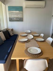 a wooden table with white plates on top of it at Aldinga Beach Break - C21 SouthCoast Holidays in Aldinga Beach