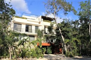 a white building with trees in front of it at Casa Bedouin Luxury 3BR A Zama Spa Private Pool in Tulum