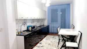 eine Küche mit Spüle und Tisch mit Stühlen in der Unterkunft 2х комнатная квартира в ЖК Отау сити in Schymkent